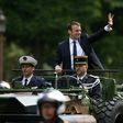 French President Emmanuel Macron (C) waves as he parades in a car on the Champs Elysees avenue after his formal inauguration ceremony on May 14, 2017 in Paris