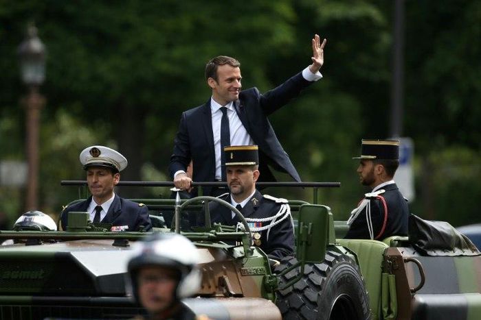 French President Emmanuel Macron (C) waves as he parades in a car on the Champs Elysees avenue after his formal inauguration ceremony on May 14, 2017 in Paris