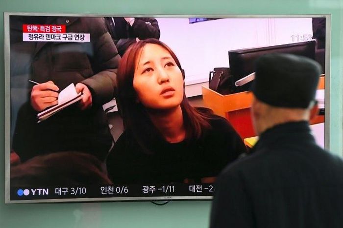 People at a railway station in Seoul look at a news report on the arrest of Chung Yoo-Ra (C), the 20-year-old daughter of the woman dubbed South Korea's "Rasputin"