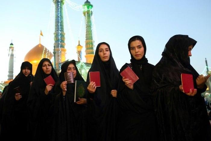Iranian women hold their IDs as they wait to vote at the Massoumeh shrine in the holy city of Qom on May 19, 2017