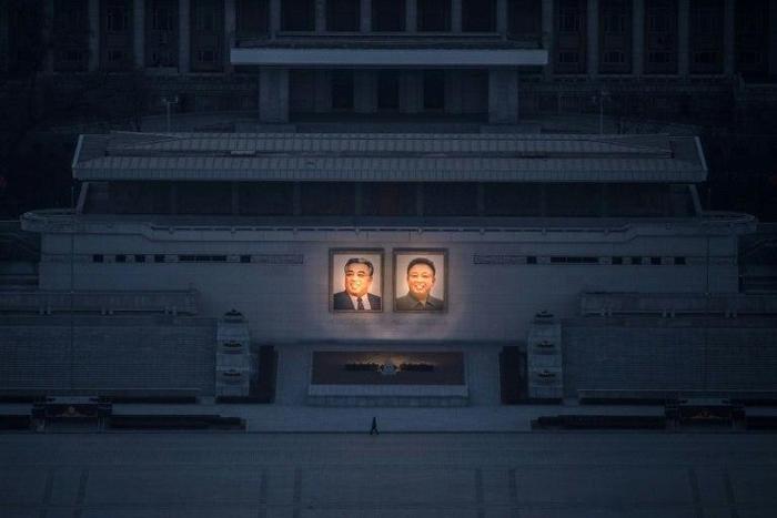 A pedestrian passes portraits of late North Korean leaders Kim Il-Sung (L) and Kim Jong-Il in Pyongyang, seen from the landmark Juche tower on February 17, 2017