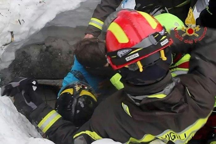 Picture released by Italy's Vigili del Fuoco fire service shows a child (C) being rescued from the Hotel Rigopiano, in the mountains of central Italy, on January 20, 2017 after they were buried under an avalanche