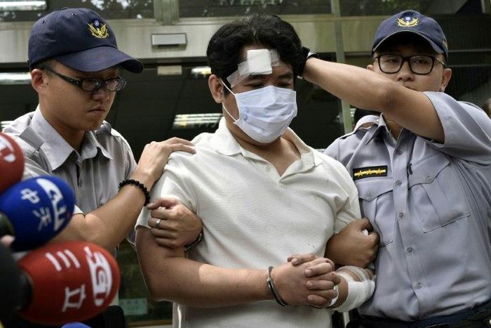 A man identified only by his family name Lu (C), is escorted by policemen after he was suspected of slashing a guard with a Samurai sword at Taiwan's Presidential Palace