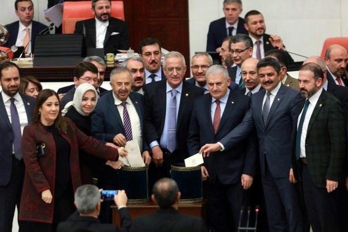 Turkish Prime Minister Binali Yildirim (3rd R) and lawmakers pose as they cast their ballots during a vote on provisions in a bill to change the constitution at the Turkish parliament in Ankara on January 14, 2017