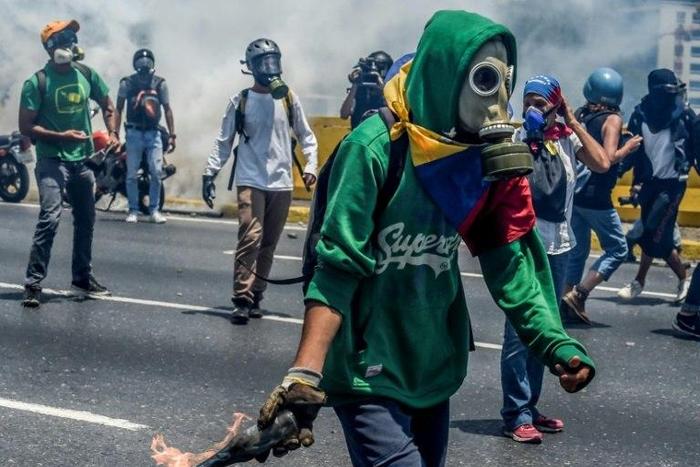 Venezuelan opposition activists clash with riot police during a protest march against President Nicolas Maduro in Caracas on April 26, 2017