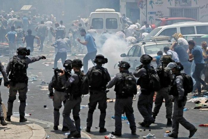 Palestinian worshippers run for cover as Israeli forces fire tear gas following protest prayers held outside Jerusalem's Old City on July 21, 2017, after police denied entry to men under 50