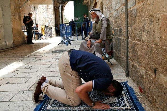 A Palestinian Muslim prays in front of a gate to the Al-Aqsa mosque compound in the Old City of Jerusalem on July 26, 2017, as a tense standoff simmers over the holy site