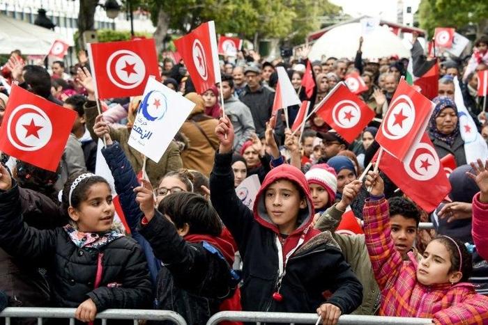 Tunisians wave their national and party flags of the Islamist Ennahdha Party during a rally on January 14, 2017 in the Habib Bourguiba Avenue in the capital Tunis to mark the sixth anniversary of the 2011 revolution
