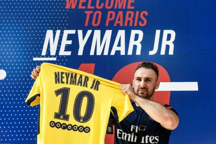 A PSG fan holds a PSG yellow away jersey, marked with the number 10 and the name of Brazilian star Neymar, after he purchased it from the Paris-Saint-Germain (PSG) football club store on the Champs Elysees avenue in Paris on August 4, 2017