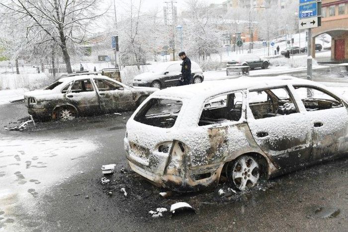 A policeman investigates a burned out car in the suburb Rinkeby, outside Stockholm, on February 21, 2017