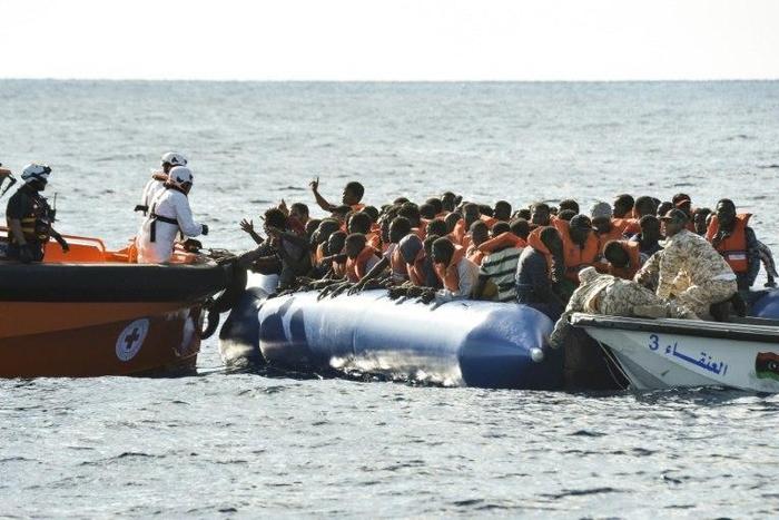 Migrants and refugees sit on a rubber boat during a rescue operation of the Topaz Responder, a rescue ship run by Maltese NGO "Moas" and the Italian Red Cross with the help of the Libyan coastguards, on November 4, 2016 off th Libyan coast