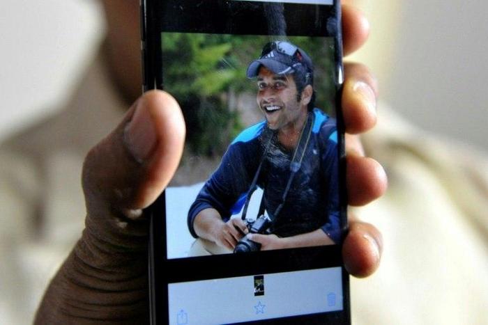 Jagan Mohan Reddy holds a smartphone with an image of his son Alok Madasani at his residence in Hyderabad on February 24, 2017, after Alok was injured in the shooting of two Indian men in the US state of Kansas