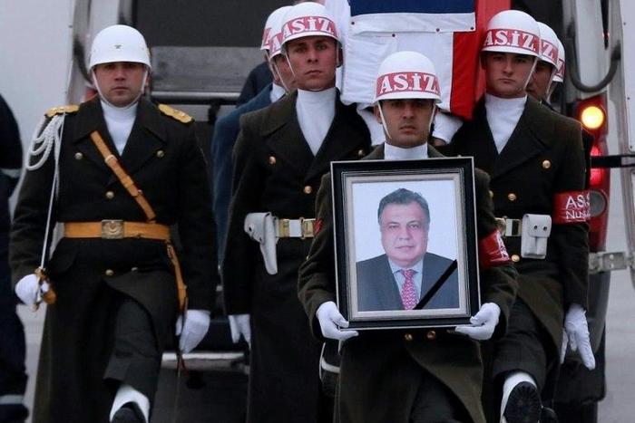 Members of a Turkish forces honour guard carry the Russian flag-draped coffin of late Russian Ambassador to Turkey Andrei Karlov and a picture of him during a ceremonial farewell with full state honours on the tarmac of Ankara's Esenboga Airport