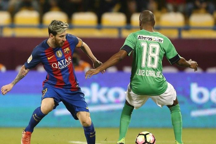FC Barcelona's Lionel Messi (L) vies with Al-Ahli's Luiz Carlos during a friendly football match between FC Barcelona and Saudi Arabia's Al-Ahli FC on December 13, 2016 in the Qatari capital Doha