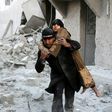 A Syrian rescuer carries a woman from the rubble of a building in Aleppo on November 20, 2016