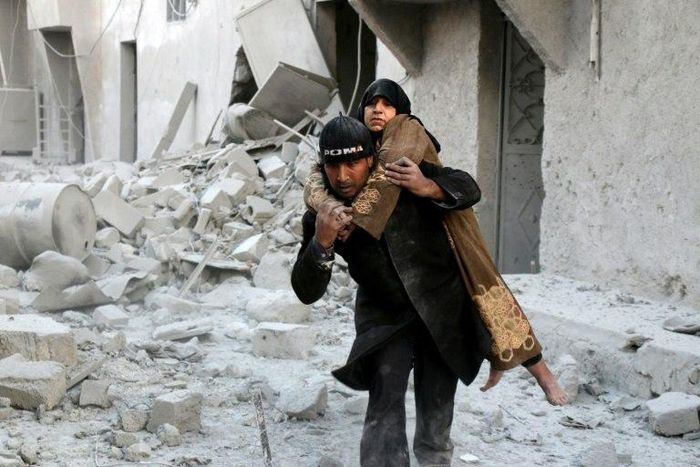A Syrian rescuer carries a woman from the rubble of a building in Aleppo on November 20, 2016