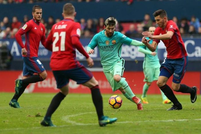 Barcelona's Argentinian forward Lionel Messi (centre) vies with Osasuna's defender David Garcia during their Spanish league match in Pamplona on December 10, 2016