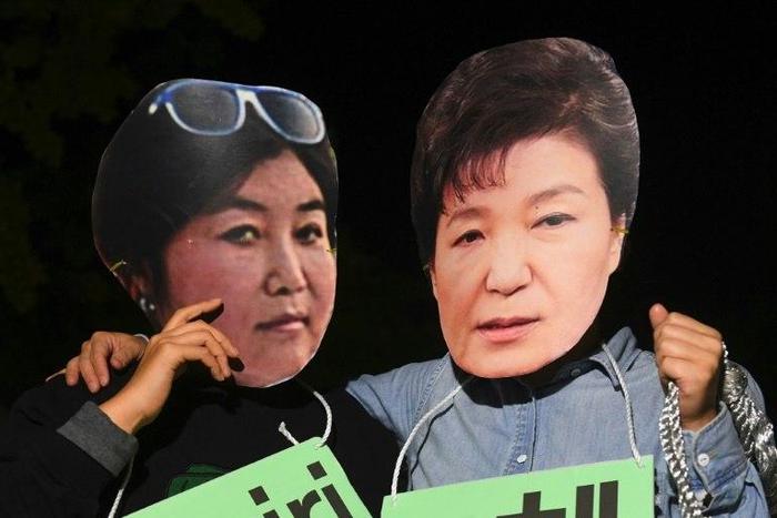 Protesters wearing masks of South Korean President Park Geun-Hye (R) and her confidante Choi Soon-Sil pose for a photo during a rally in Seoul, on October 27, 2016
