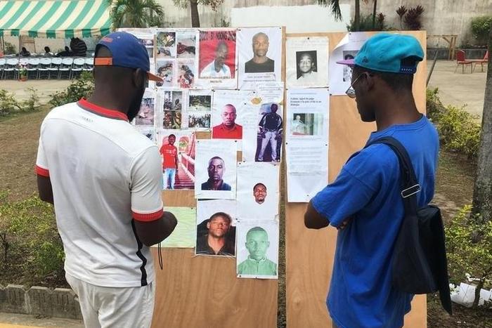 Men examine a poster board showing people who died or are still missing following clashes after elections in Libreville, Gabon, September 19, 2016.