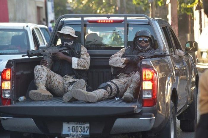 Haitian police stand guard outside a radio station after the arrest there of former coup leader Guy Philippe, long wanted by US authorities on drug trafficking charges