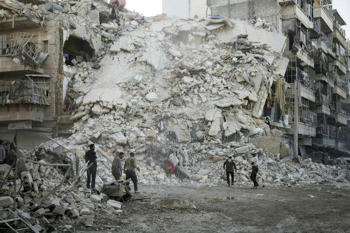 Members of the White Helmets search for victims amid the rubble of a destroyed building following reported air strikes in Aleppo, on October 17, 2016
