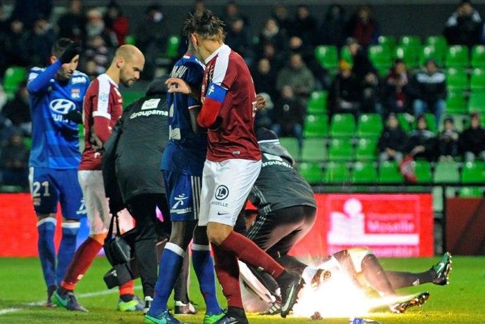 A firecracker explodes beside Lyon and Metz players during the French L1 football match between Metz (FCM) and Lyon (OL) on December 3, 2016 at Saint Symphorien stadium in Longeville-Les-Metz, eastern France