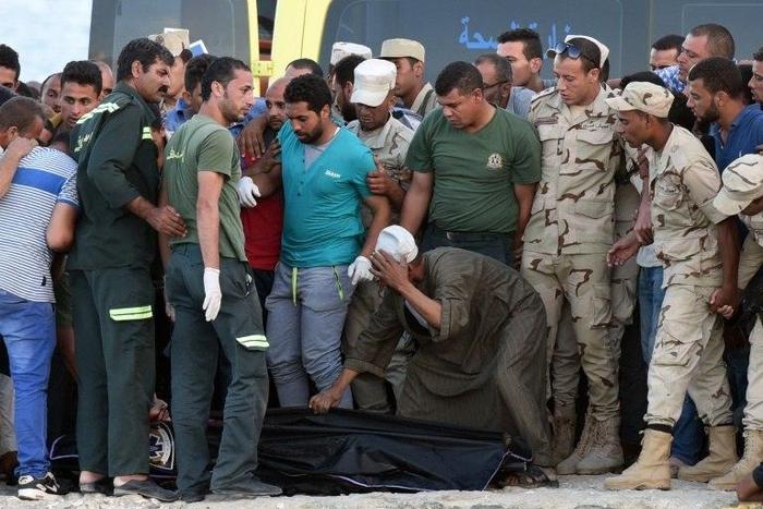 Policemen and medics gather around the body of a migrant along the shore in the Egyptian port city of Rosetta on September 22, 2016, during a search operation after a boat capsized in the Mediterranean