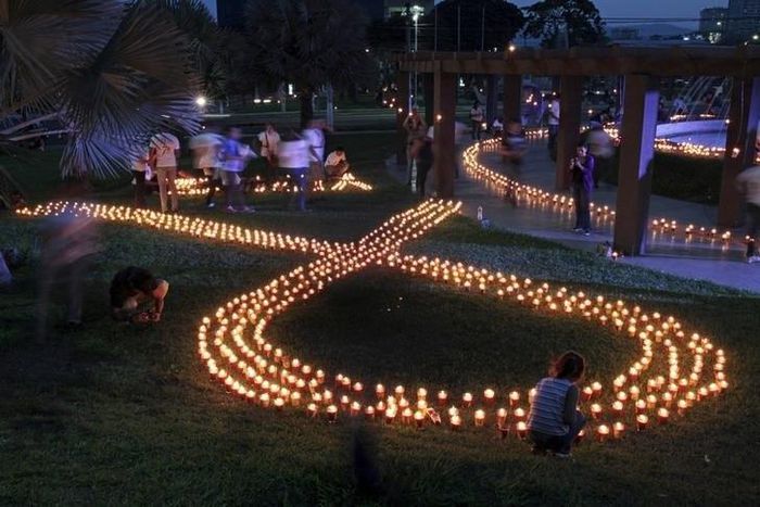 Volunteers light up candles in the shape of an HIV/AIDS awareness "Red Ribbon" during the International AIDS Candlelight Memorial in San Salvador May 17, 2015. REUTERS/Jose Cabezas/Files