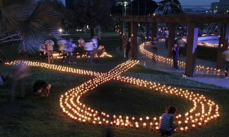 Volunteers light up candles in the shape of an HIV/AIDS awareness "Red Ribbon" during the International AIDS Candlelight Memorial in San Salvador May 17, 2015. REUTERS/Jose Cabezas/Files