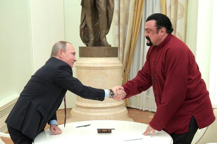 Vladimir Putin (left) shakes hands with Steven Seagal after presenting him with a Russian passport during a meeting at the Kremlin in Moscow, on November 25, 2016