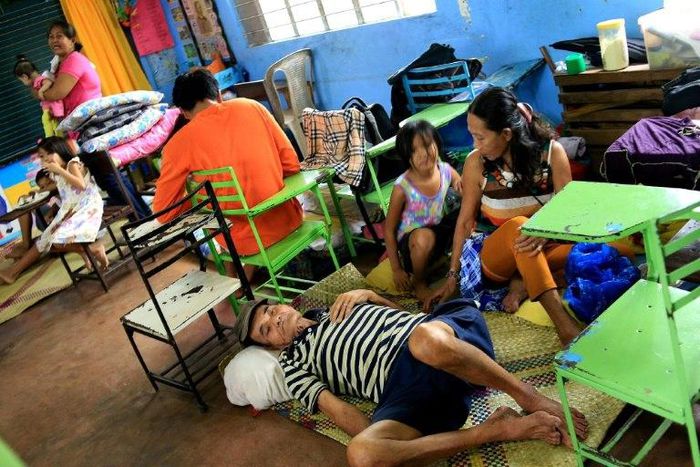 Residents sit inside a classroom at the Central Elementary School which has been turned into an evacuation centre, in Santo Domingo, central Philippines' Albay province, on December 25, 2016, due to approaching Typhoon Nock-Ten