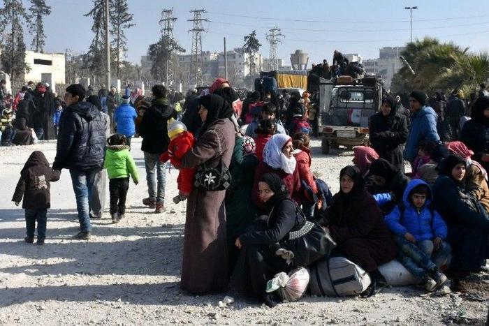 Syrian civilians wait a checkpoint manned by pro-government forces after leaving Aleppo's eastern neighbourhoods on December 10, 2016