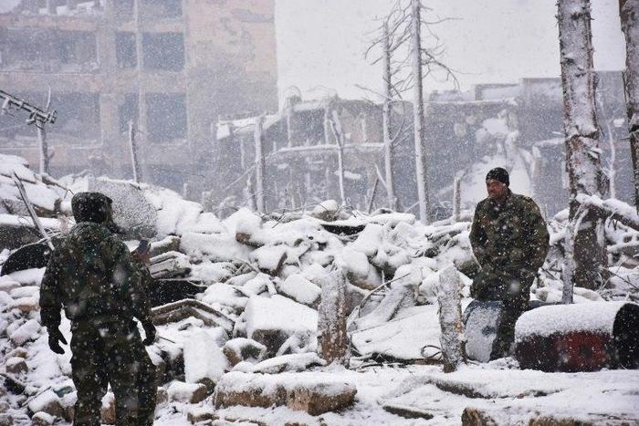 Syrian troops walk in the snow in Aleppo on December 21, 2016