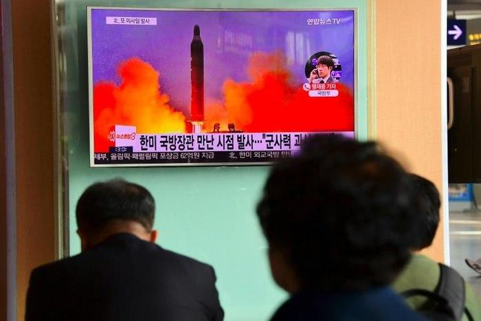 People watch a television news report showing file footage of North Korea's missile launch at a railway station in Seoul on October 20, 2016