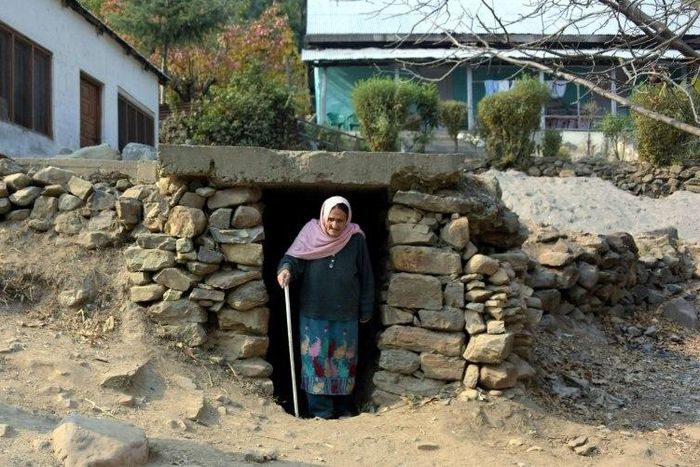 A Pakistani Kashmiri woman walks out of an underground bunker in Athmuqam village on the Line of Control, the de facto border between Pakistan and India,