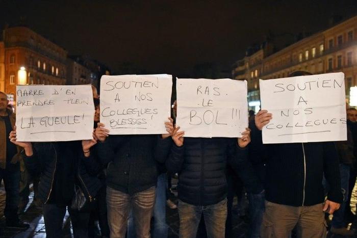 Demonstrators hold placards reading "Tired of getting our ass kicked !, Support for our wounded colleagues, Enough !" as they take part in a rally of French police officers in front of the war memorial to protest over mounting attacks on officers