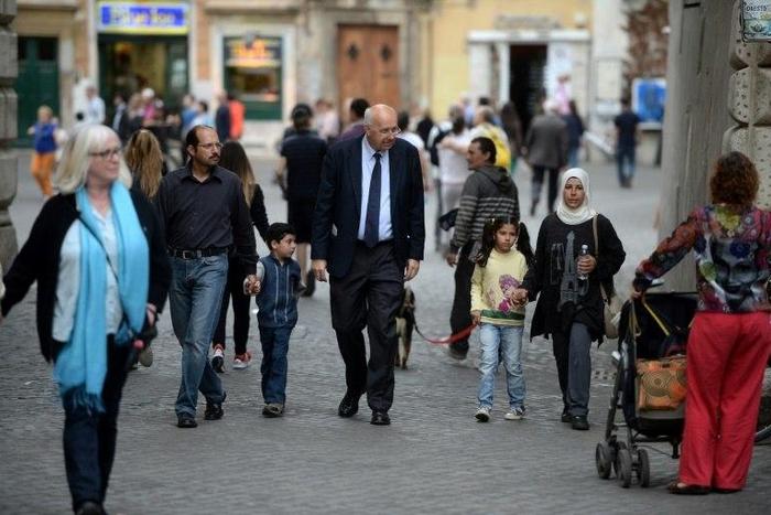 A family of Syrian refugees part of the 12 Syrian asylum seekers Pope Francis brought back with him from Greek island Lesbos, walk with a member of the St. Egidio Roman Catholic Charity (C), on April 18, 2016 in a strret of Rome