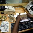 A teller arranges Kenya shilling coins and notes inside the cashier's booth at a forex exchange bureau in Kenya's capital Nairobi, April 20, 2016. REUTERS/Thomas Mukoya