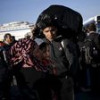 An Afghan refugee carries his belongings as he and his family wait to board a bus, following the arrival of refugees and migrants by the Blue Star Patmos passenger ferry from the island of Lesbos at the port of Piraeus, near Athens, Greece, October 14,...