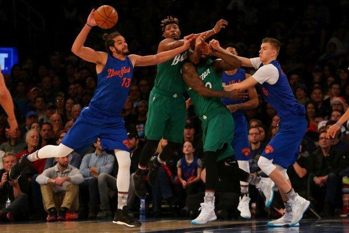 Joakim Noah and Kristaps Porzingis of the New York Knicks pursue the loose ball against Marcus Smart and Amir Johnson of the Boston Celtics at Madison Square Garden on December 25, 2016