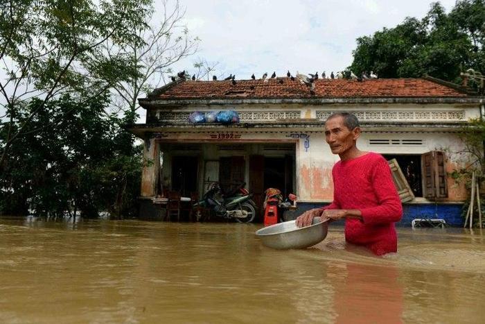 A man wades through floodwaters in front of his home in the central Vietnamese province of Binh Dinh on December 18, 2016