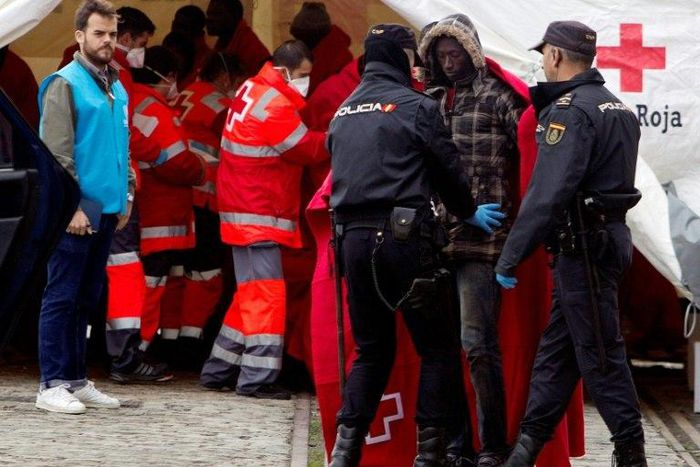Immigrants are frisked by police officers following their arrival on board of a Spanish coast guard vessel into the southern Spanish port of Malaga on December 3, 2016