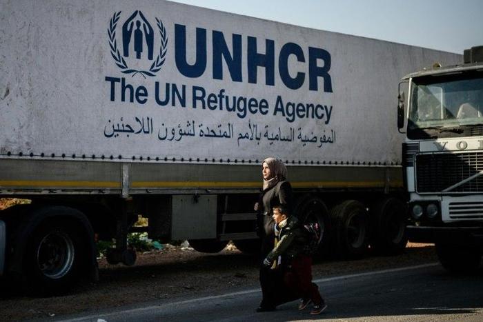 A Syrian woman with her child walks near a Syrian-bound truck loaded with humanitarian aids at the UN transhipment hub at Cilvegozu in Reyhanli near the Turkish-Syrian border in Hatay on November 28, 2016