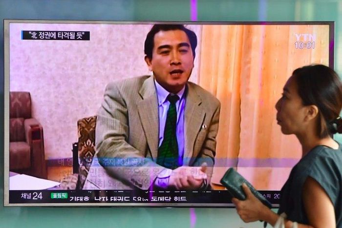 A woman walks past a television screen showing file footage of Thae Yong-Ho in Seoul on August 18, 2016