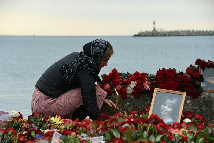 A woman lights a candle at a memorial to one of the victims of the Black Sea plane crash, famous Russian charity activist and founder of the Voters' League Yelizaveta Glinka, on the shores of the Black Sea in Sochi on December 27, 2016