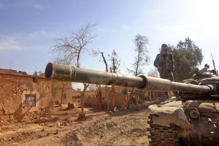 A Syrian army soldier stands atop a tank in the town of Houwayqa, in Deir Ezzor, which is almost totally under IS control