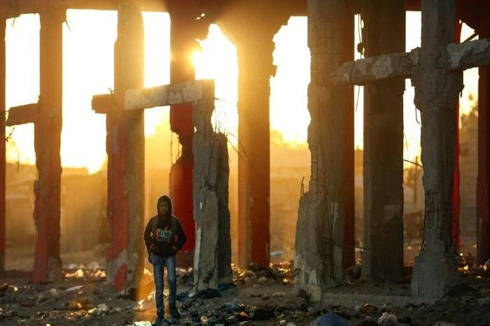 A Palestinian boy stands amidst the ruins of a building destroyed during the 50-day war between Israel and Hamas militants during the summer of 2014