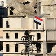 Syrian pro-government forces wave the Syrian flag on top of an electricity pole as buses evacuate rebel fighters and their families from rebel-held neighbourhoods in Aleppo