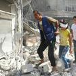 Syrians walk over rubble following air strikes on Aleppo on October 12, 2016
