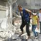 Syrians walk over rubble following air strikes on Aleppo on October 12, 2016